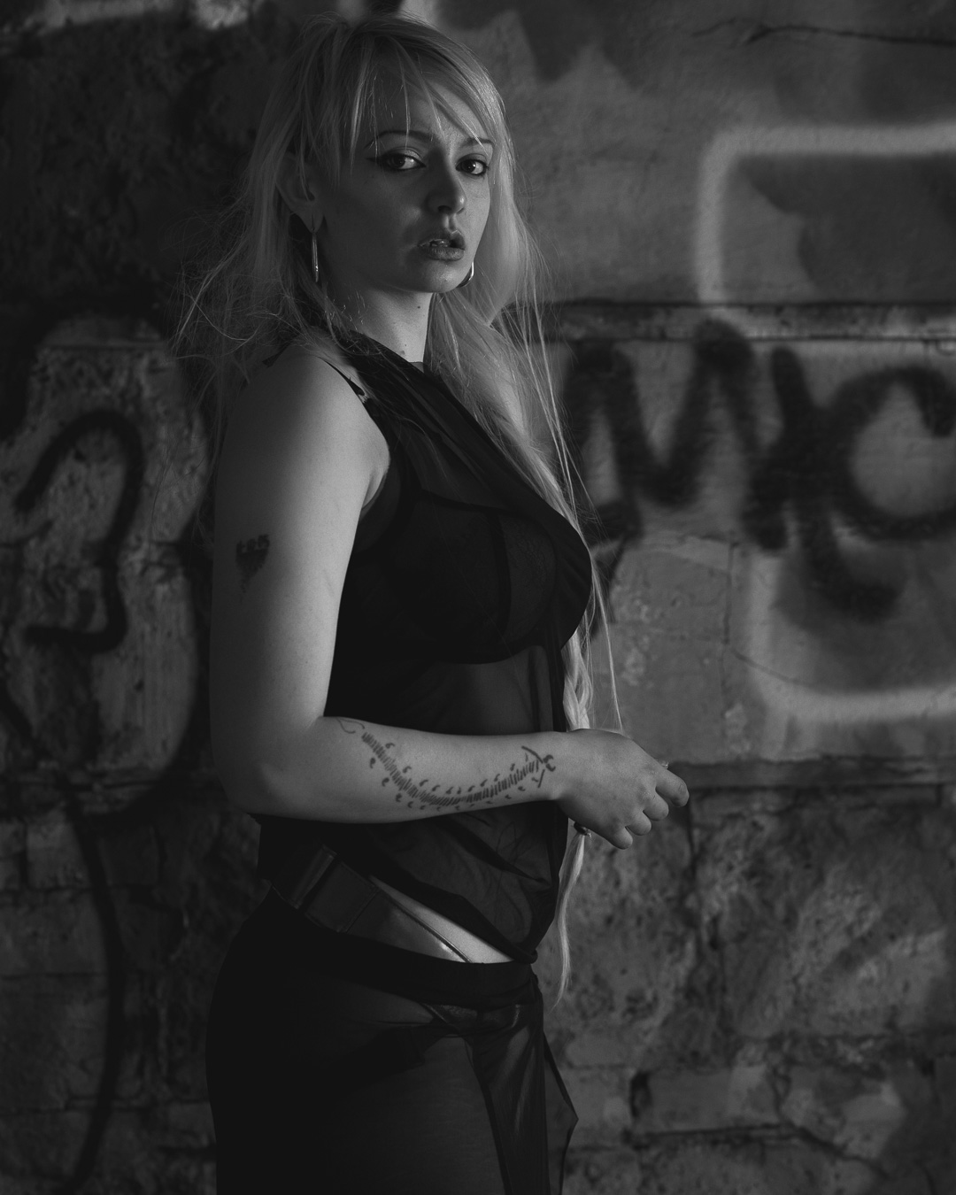 Czarno-biały filmowy portret blondynki przy ścianie z graffiti